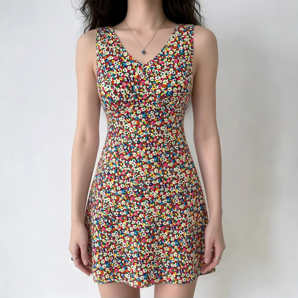 Full-body shot of a woman wearing a sleeveless colorful floral print mini dress.