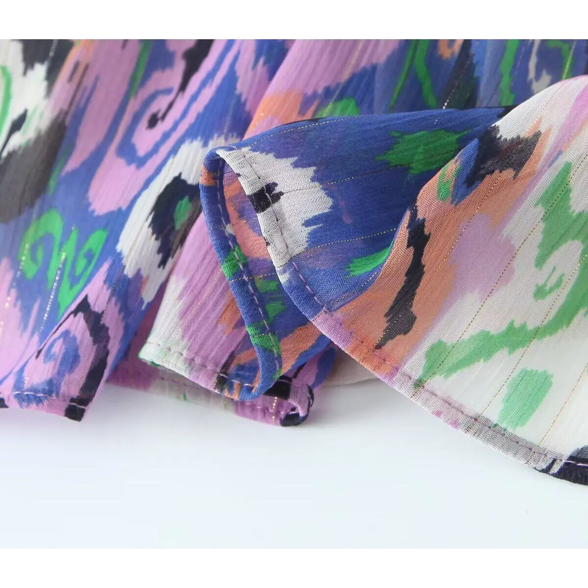 Close-up of the neatly stitched hem on the tiered ikat print dress.
