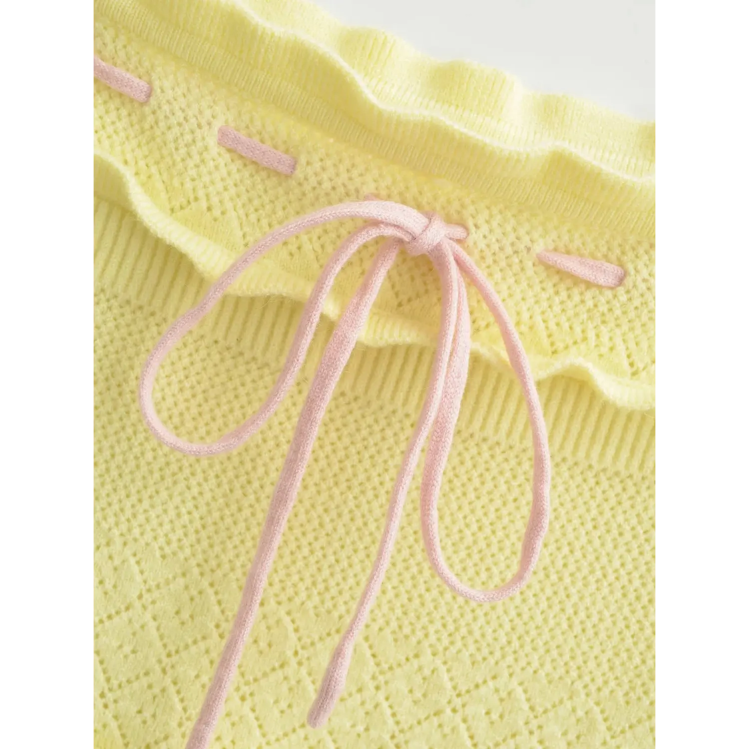 Macro shot soft pink drawstring knot, matching decorative stitching on knit bust band