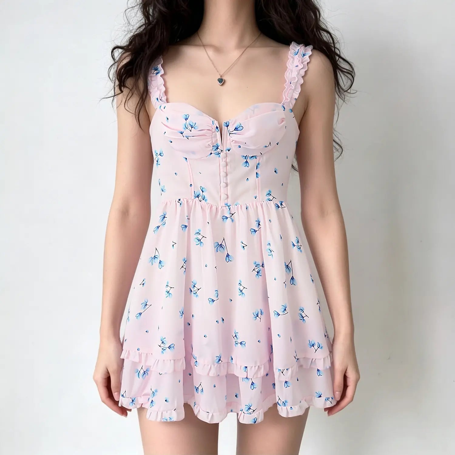 Female model wearing pink blue floral mini dress, ruffle shoulder straps, ruched bust, layered ruffle skirt, casual studio background