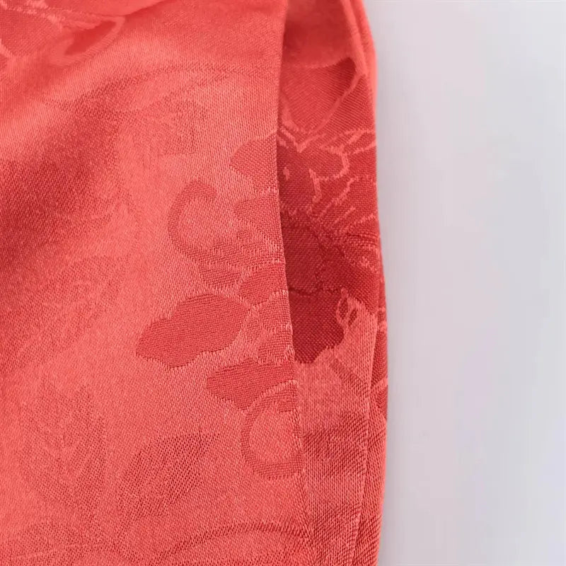 Ankle hem macro shot long shaggy coral red tassel fringe trim, secure seam attachment to jacquard pant body