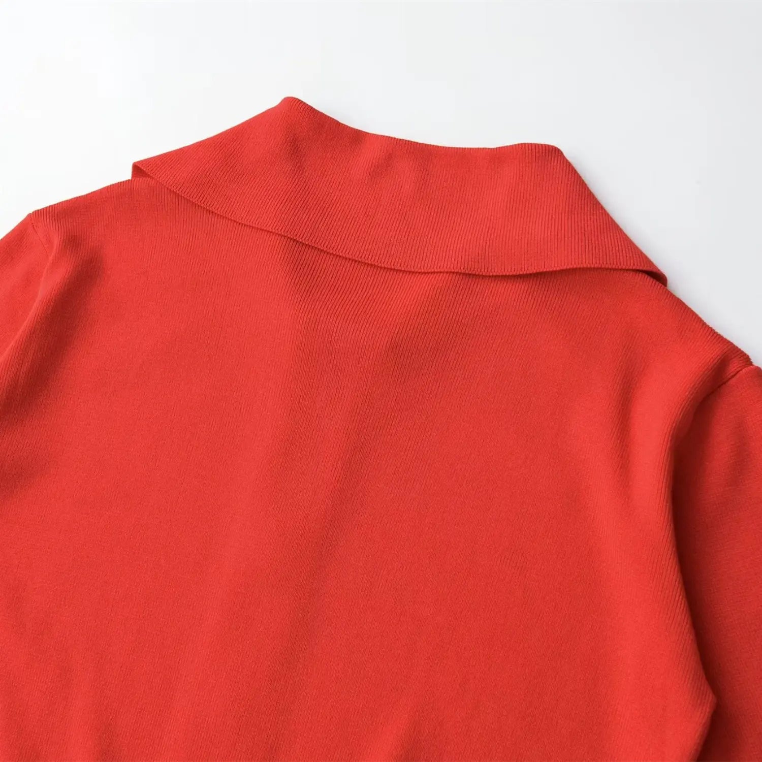 Close-up of the back of the wide pointed collar on the coral red knit top