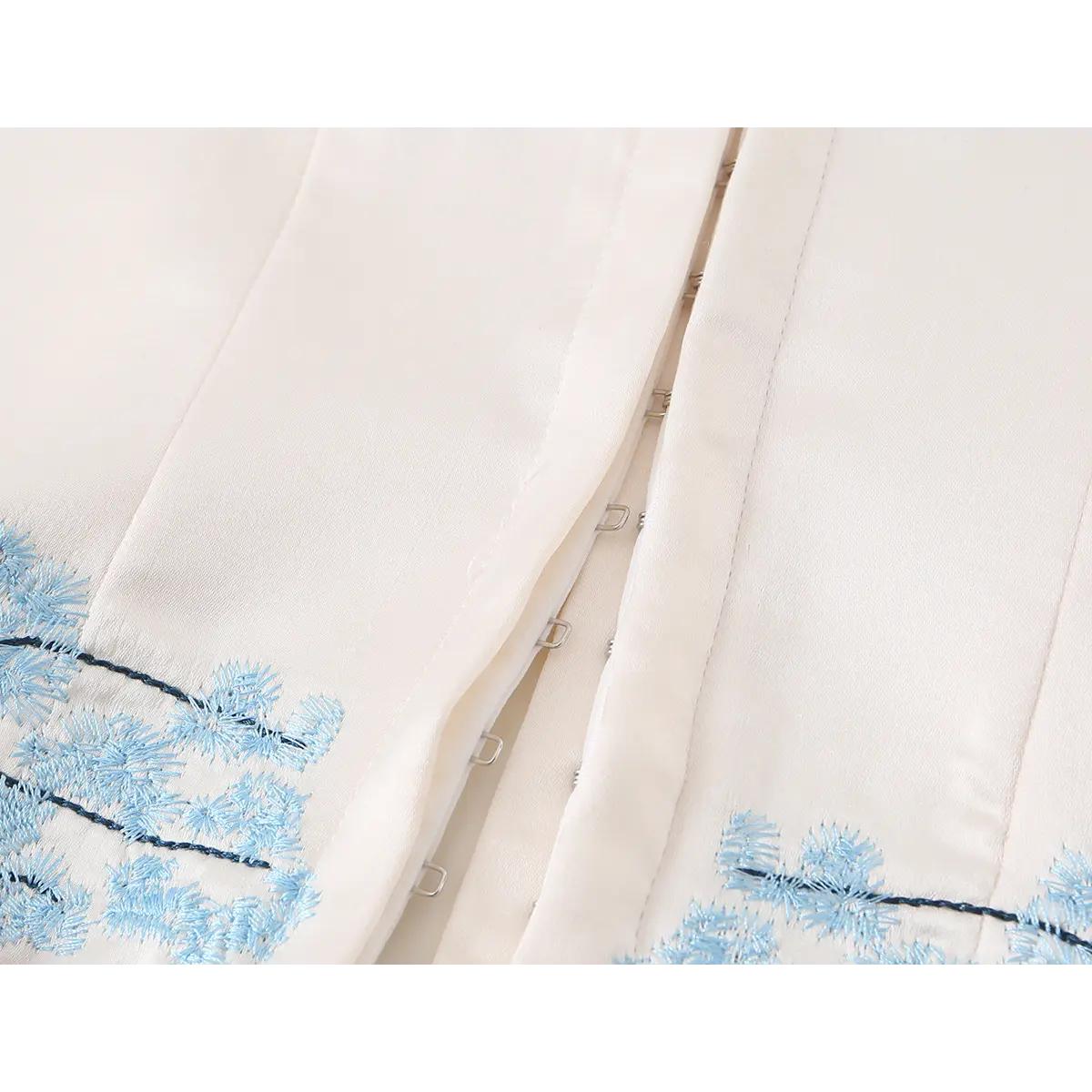 Beige satin strapless corset top with blue floral embroidery, showing hook closure detail for a fitted look.