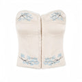 Full front studio shot of beige satin strapless corset top with blue floral embroidery and lace trim.