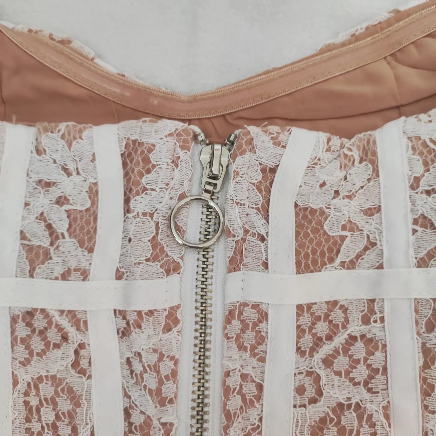 Macro close-up, silver ring pull metal zipper on the back of white lace corset dress