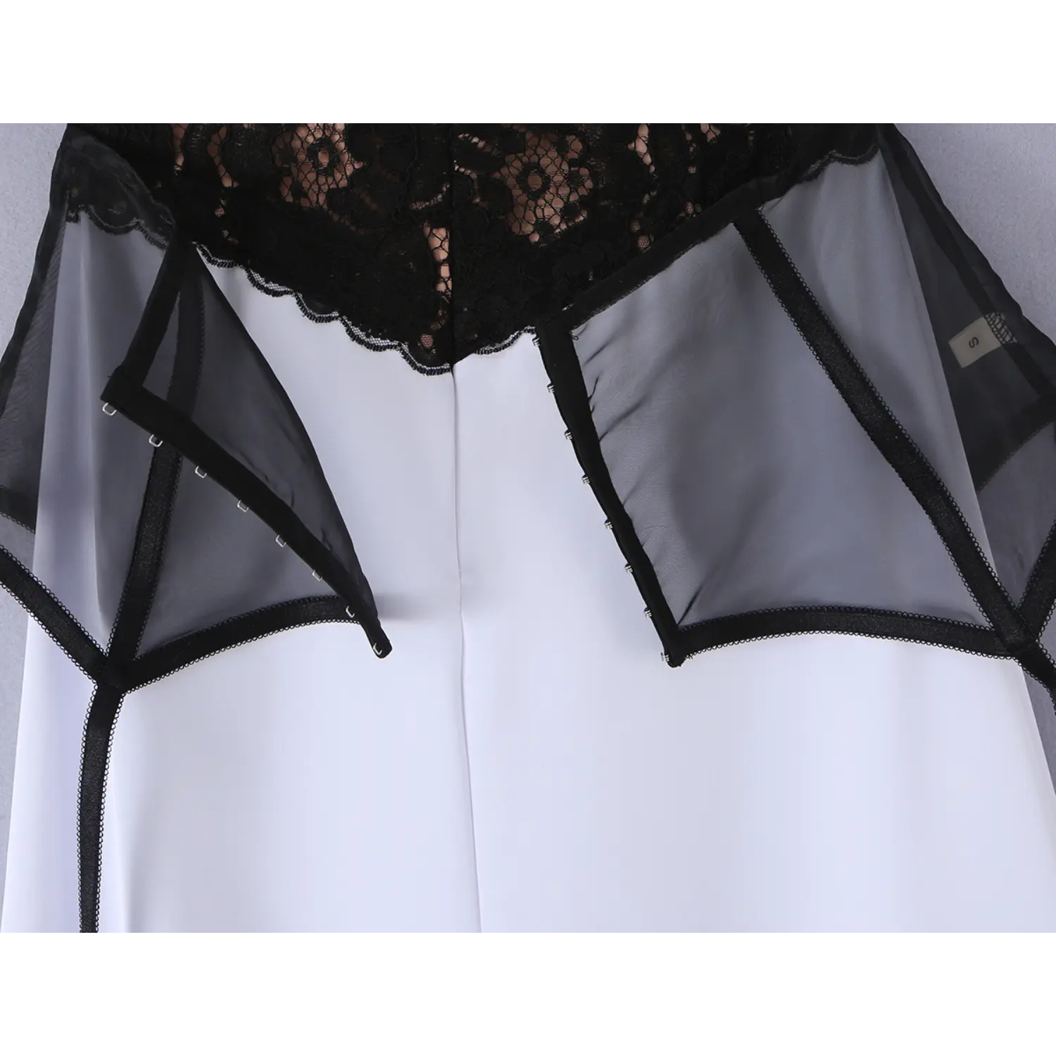 Back partial shot of black mesh corset overlay, vertical metal hook-and-eye closure, scalloped lace upper edge and structured mesh panels