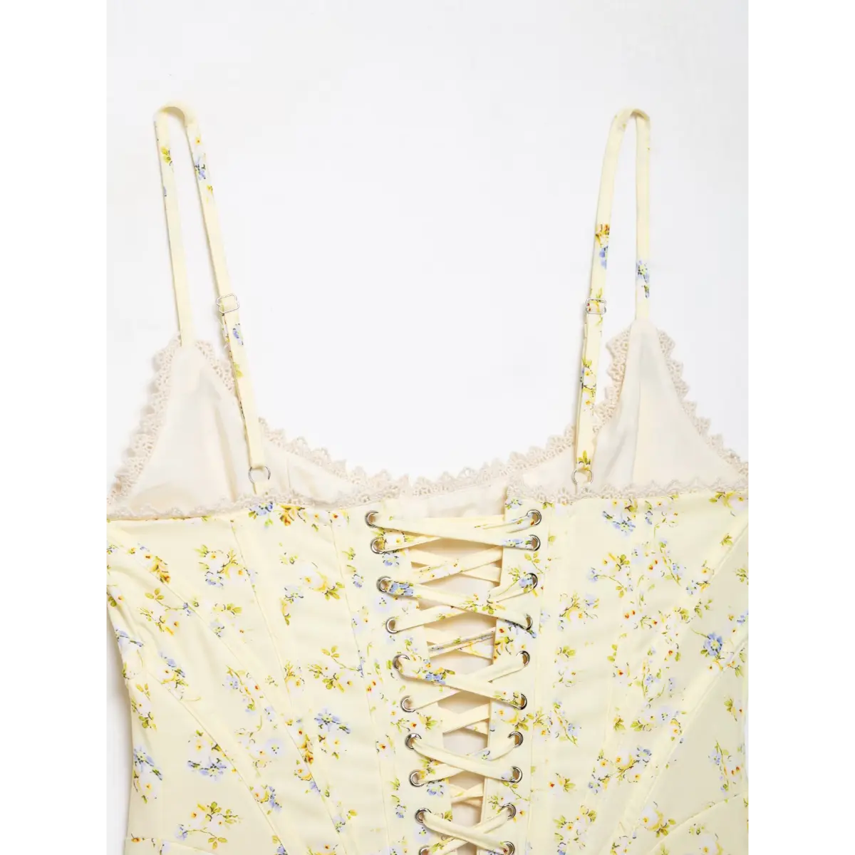 Macro close-up of fabric and lace-up texture on the back of pale yellow floral corset top.