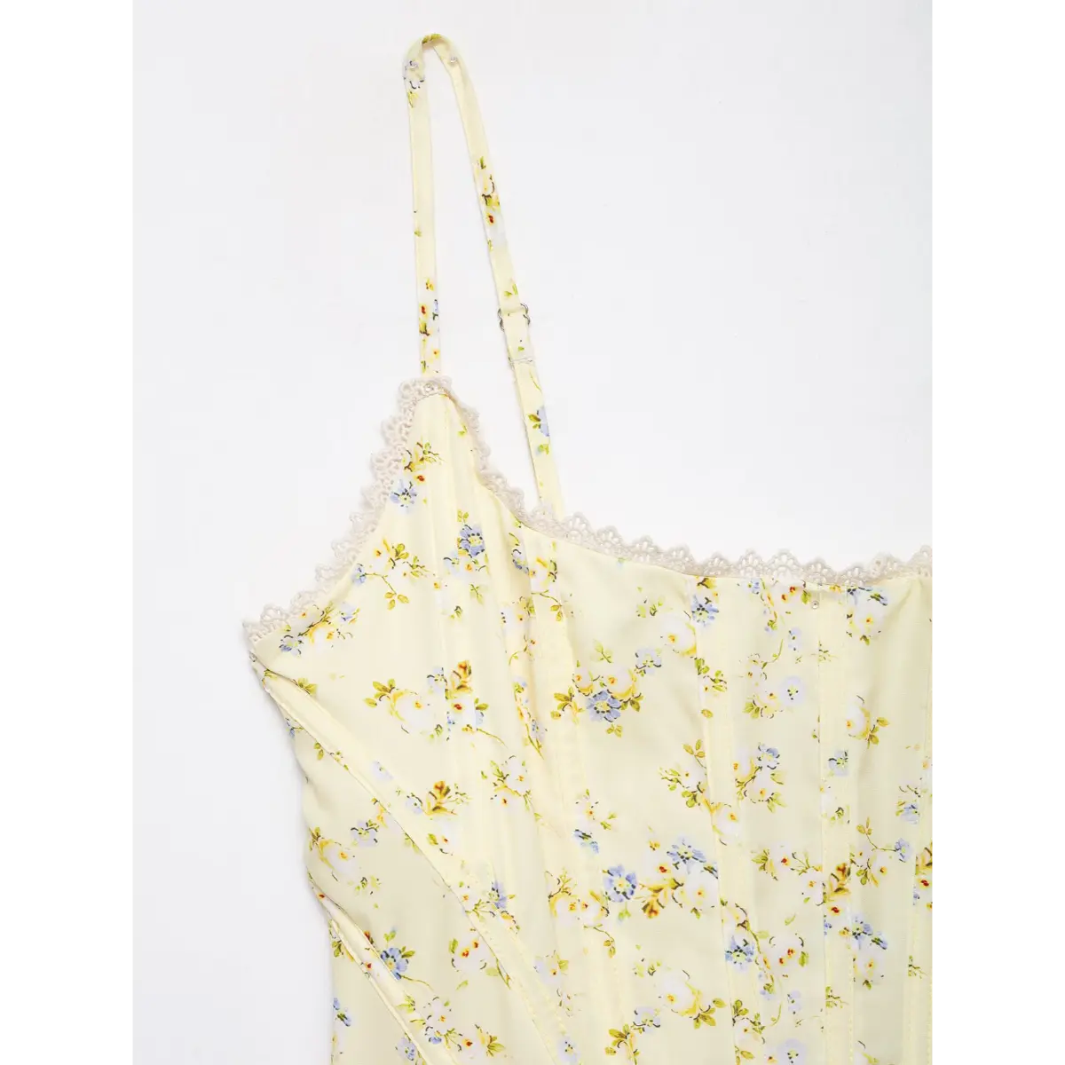 Close-up of strap edge and lace decoration on pale yellow floral print corset top.