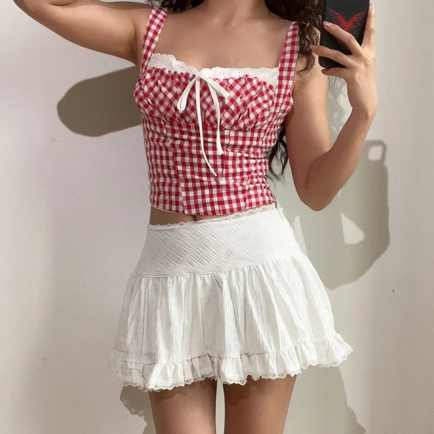 Mirror selfie full body lifestyle photo of red checkered lace cami crop top, paired with white textured ruffle mini skirt with delicate lace waist trim