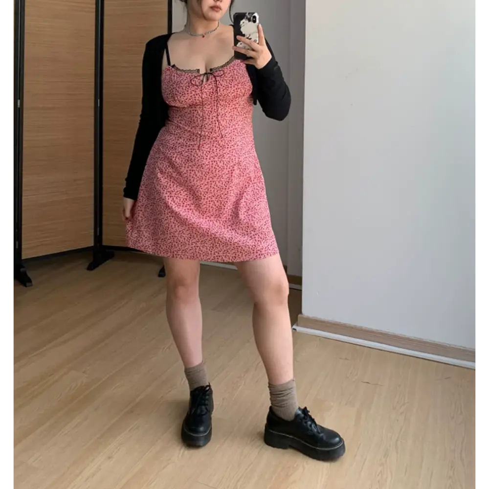 Full body indoor mirror lifestyle shot of pink ditsy floral cami mini dress, layered with slim black long sleeve cropped cardigan, matching platform loafers and gray socks