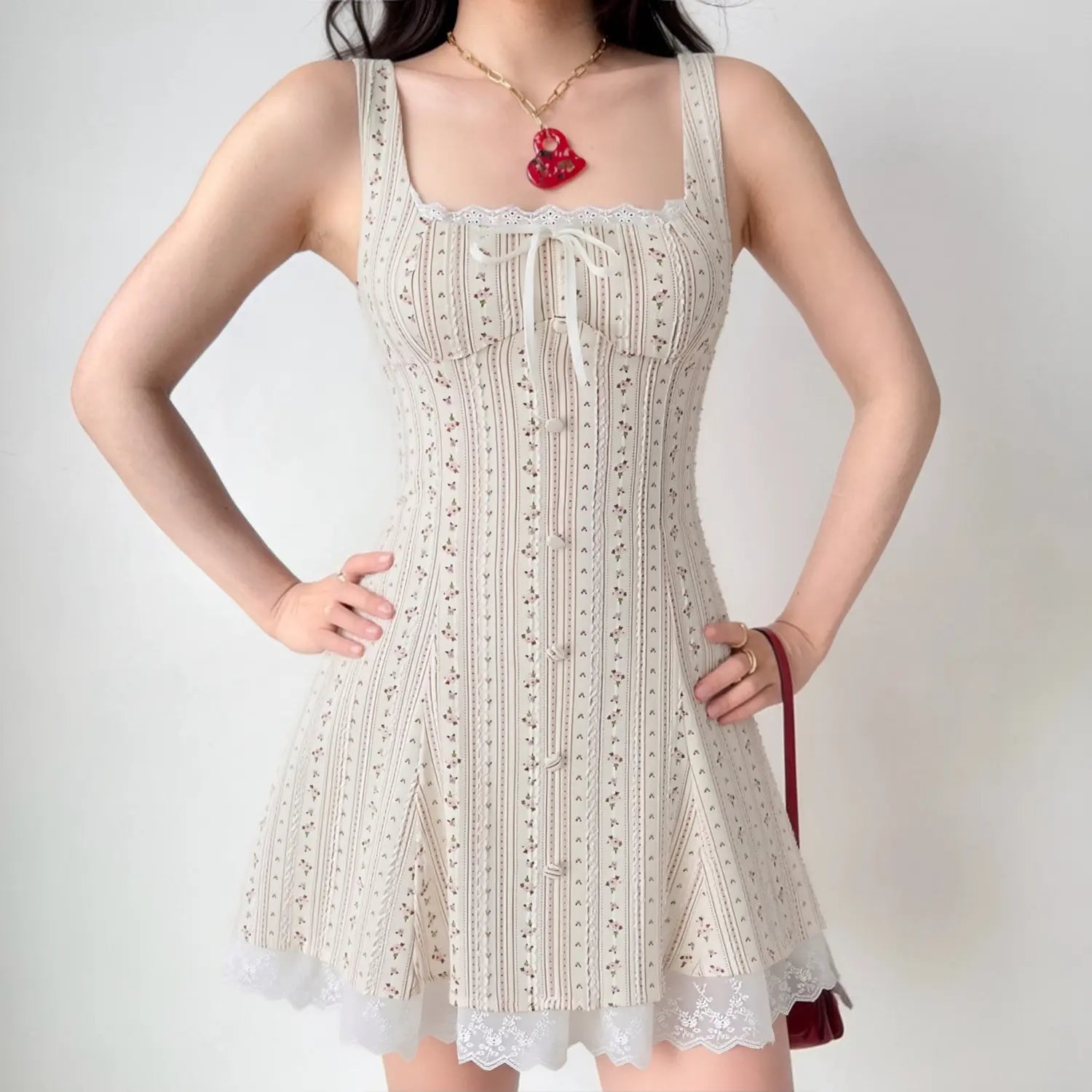 Model wearing vintage pink vertical floral strap mini sundress, lace trim square neck with front bow, corset lace-up open back, layered lace hem, sweet daily romantic cottagecore outfit