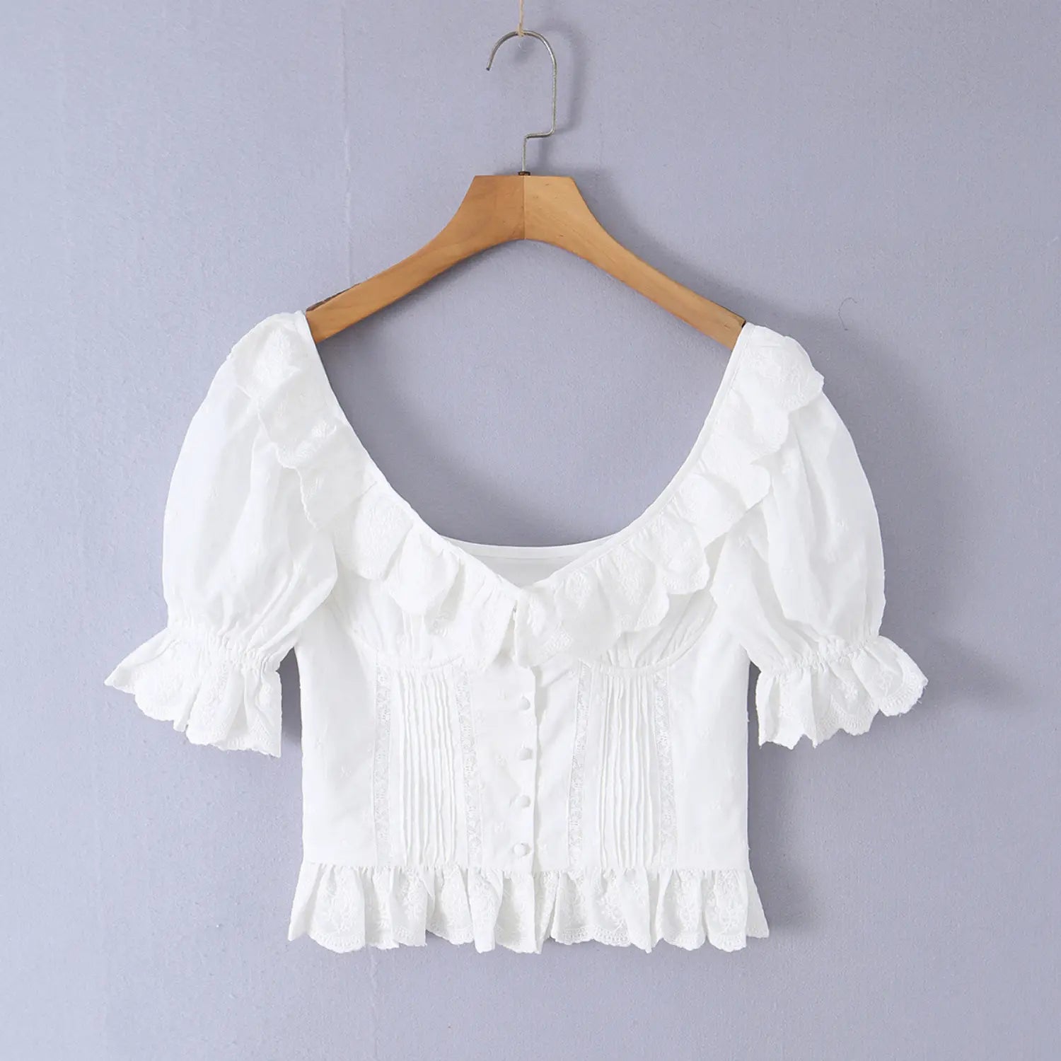 Hanging product photo white ruffle corset blouse on wooden hanger, front button pleated waist scalloped lace neck puff short sleeve
