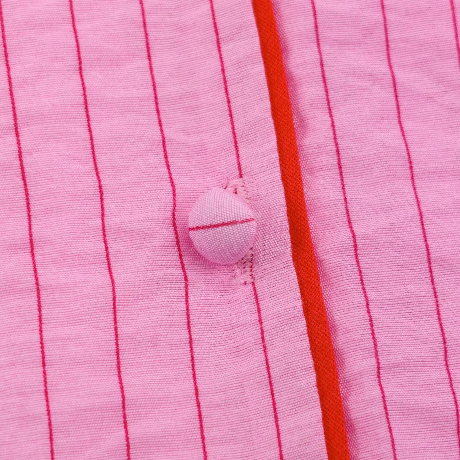 Extreme closeup pink fabric covered round button and contrast red piping