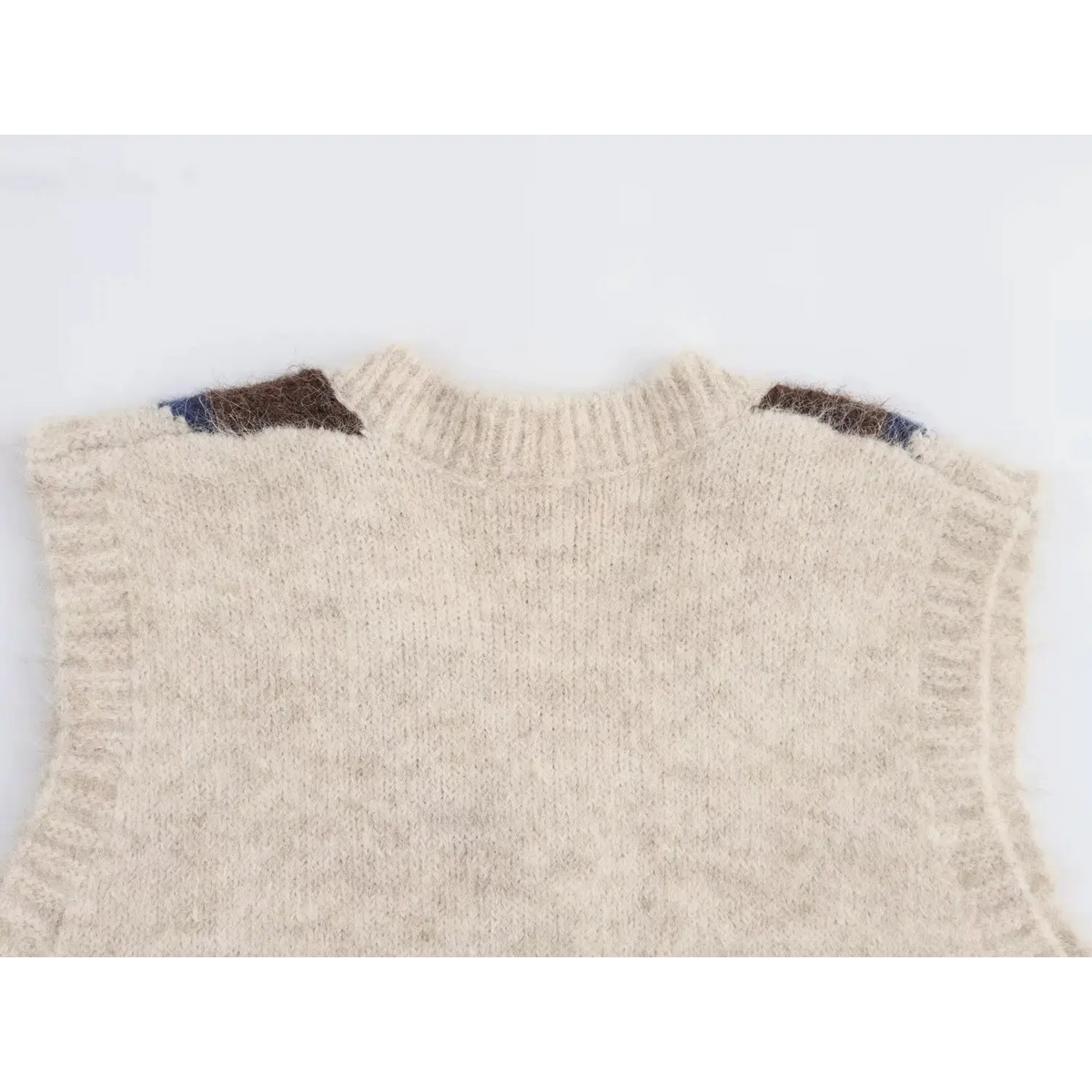 Back neck close-up of cream fuzzy knit vest, solid cream back with small argyle patch on shoulder