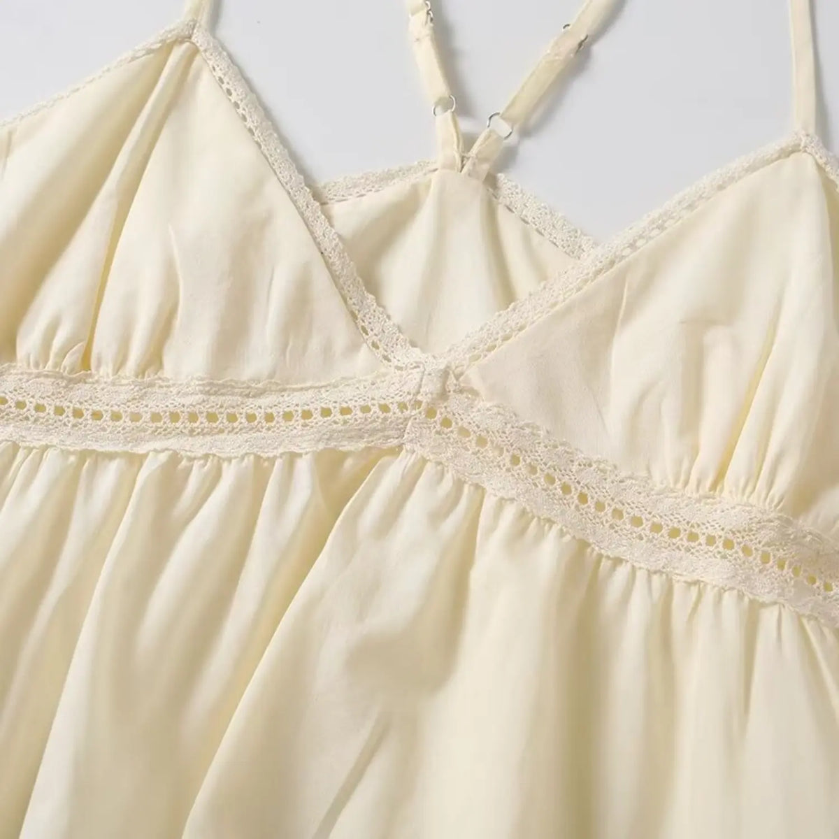 Close up of cream camisole lace neckline, eyelet lace stitching and wrapped v design