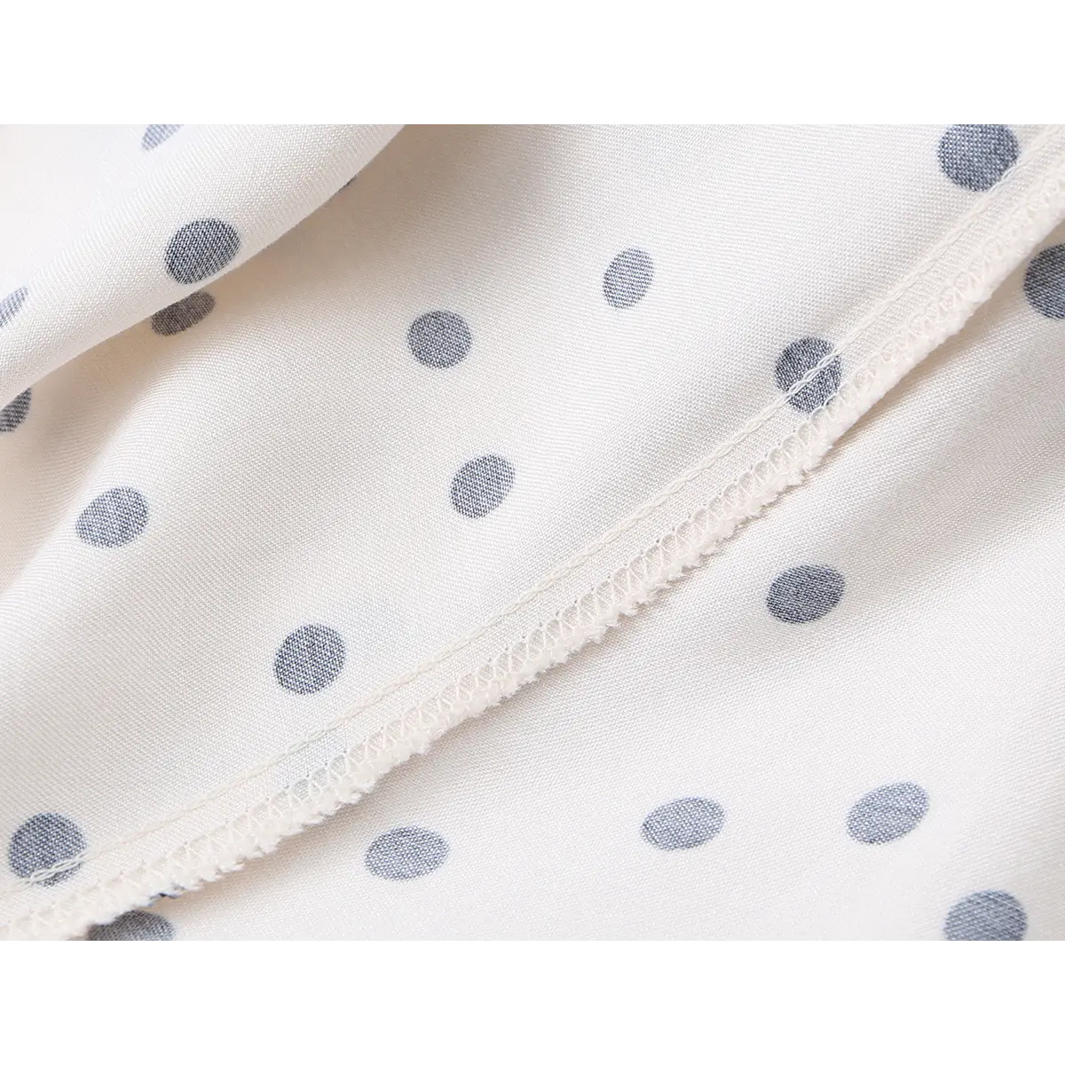 Close-up of the dress's fabric, showing the texture of the material and the slightly muted polka dots on the inner lining.