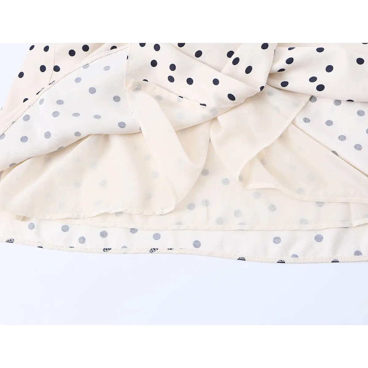Close-up of the dress's hem, showing the outer layer and the lighter, polka-dotted inner lining.