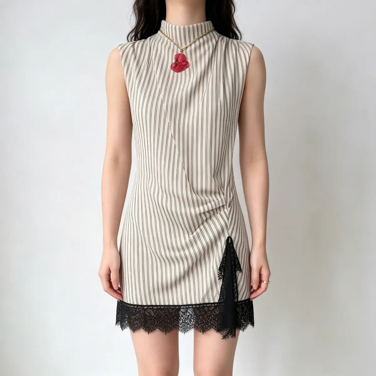 Model wearing a cream and black striped high-neck mini dress with a draped front detail and black lace trim at the hem.