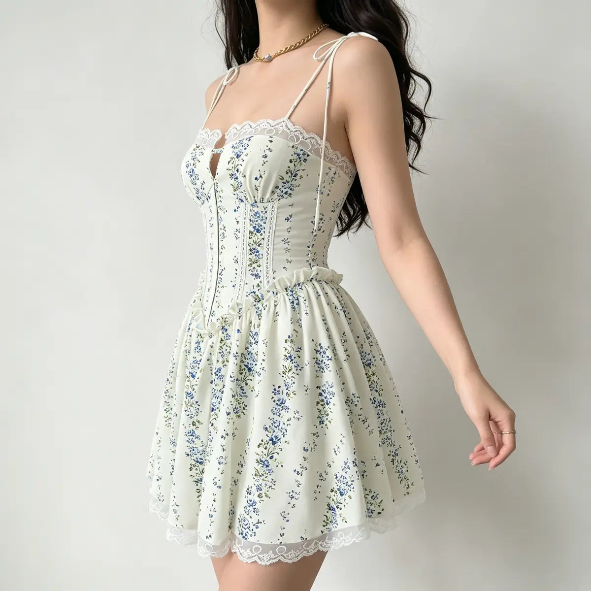 Side view of a model wearing a cream floral corset-style mini dress with lace trim and tie straps.