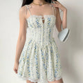 Model wearing a cream blue floral corset-style mini dress with lace trim, tie straps, and lace hem.