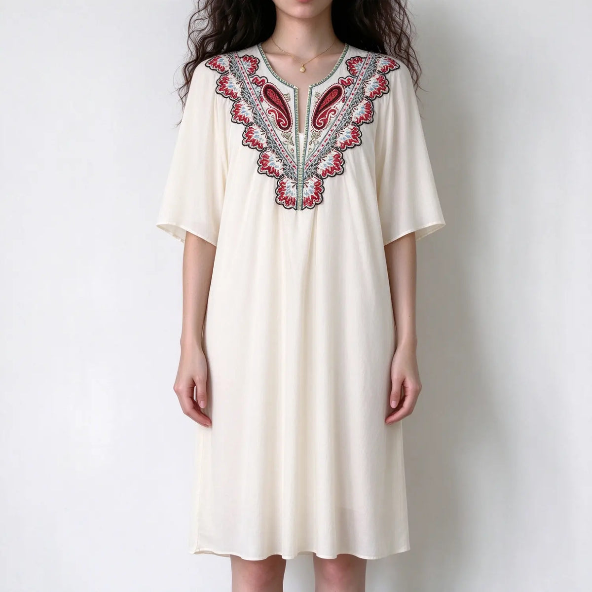 Model wearing cream boho midi dress with colorful floral embroidery on v neck, loose flowy silhouette, elbow length sleeves, white background