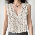 Front lifestyle shot on model of cream brown polka dot sleeveless blouse, deep v neck wavy frill trim, vintage casual summer outfit
