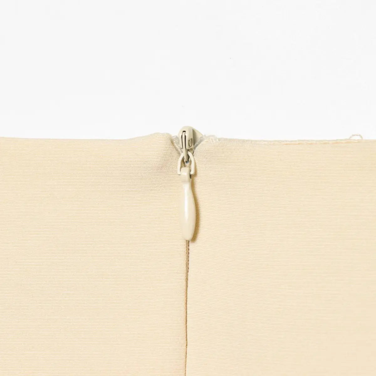  Close-up of the invisible back zipper on the cream sleeveless dress.
