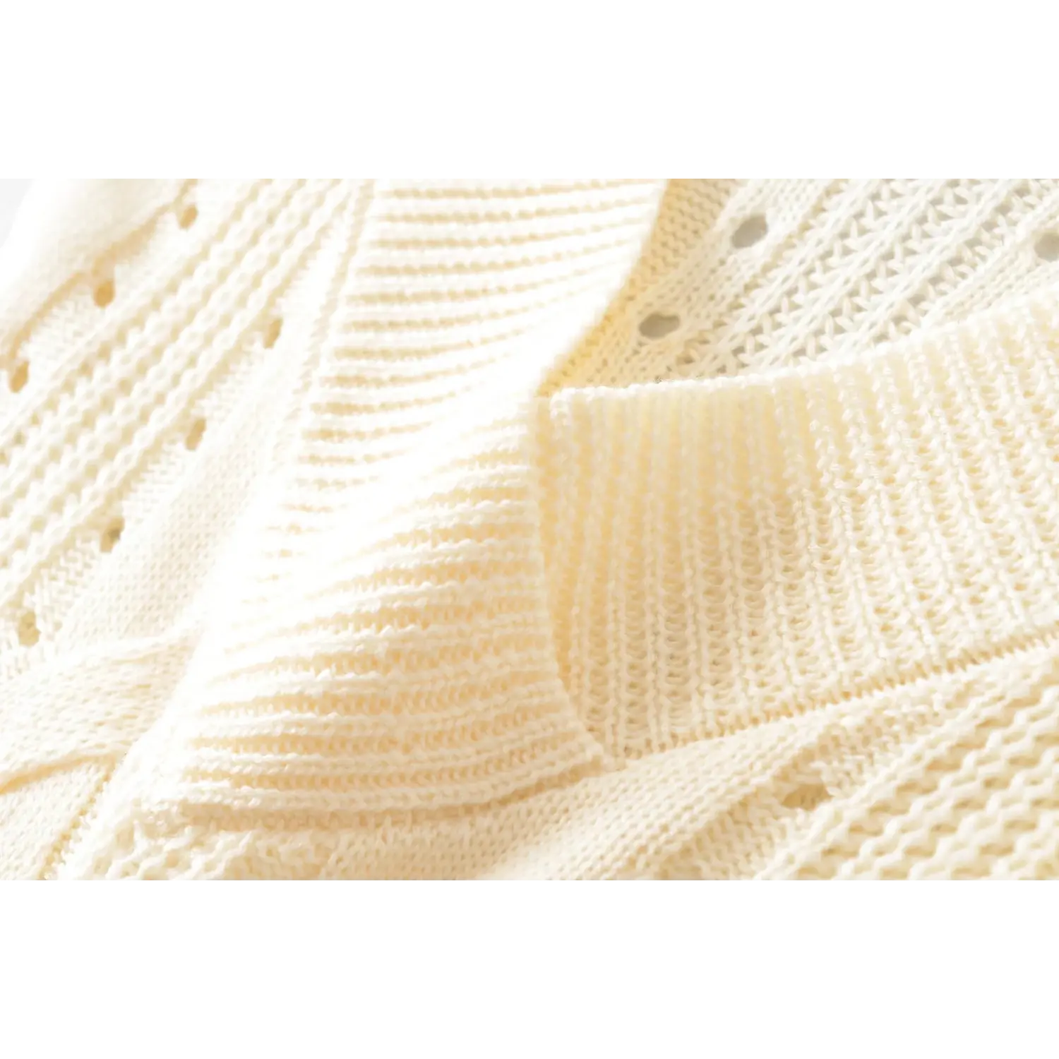 Macro texture shot of cream hollow cable knit soft lightweight women knit top fabric weave detail