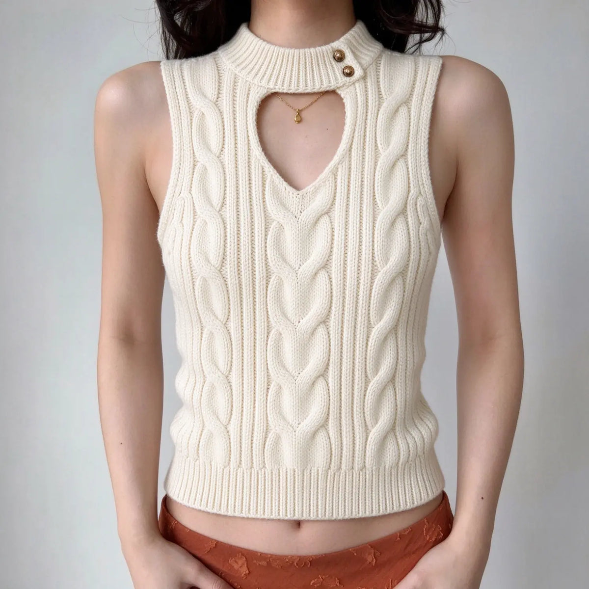 Model wearing cream cable knit mock neck cutout vest top, front view