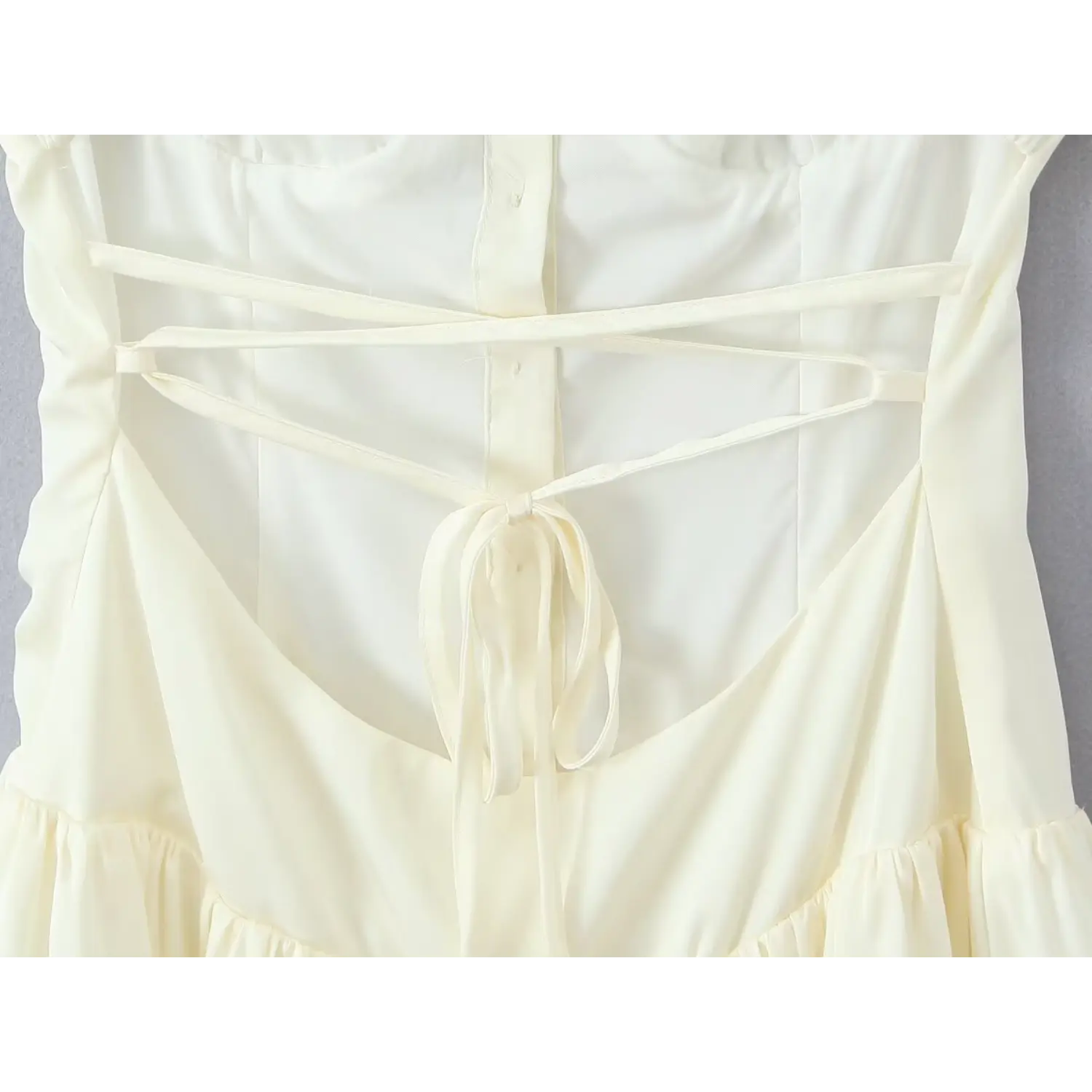 Extreme close‑up crisscross lace‑up tie bow and inner back button placket cream cami mini dress