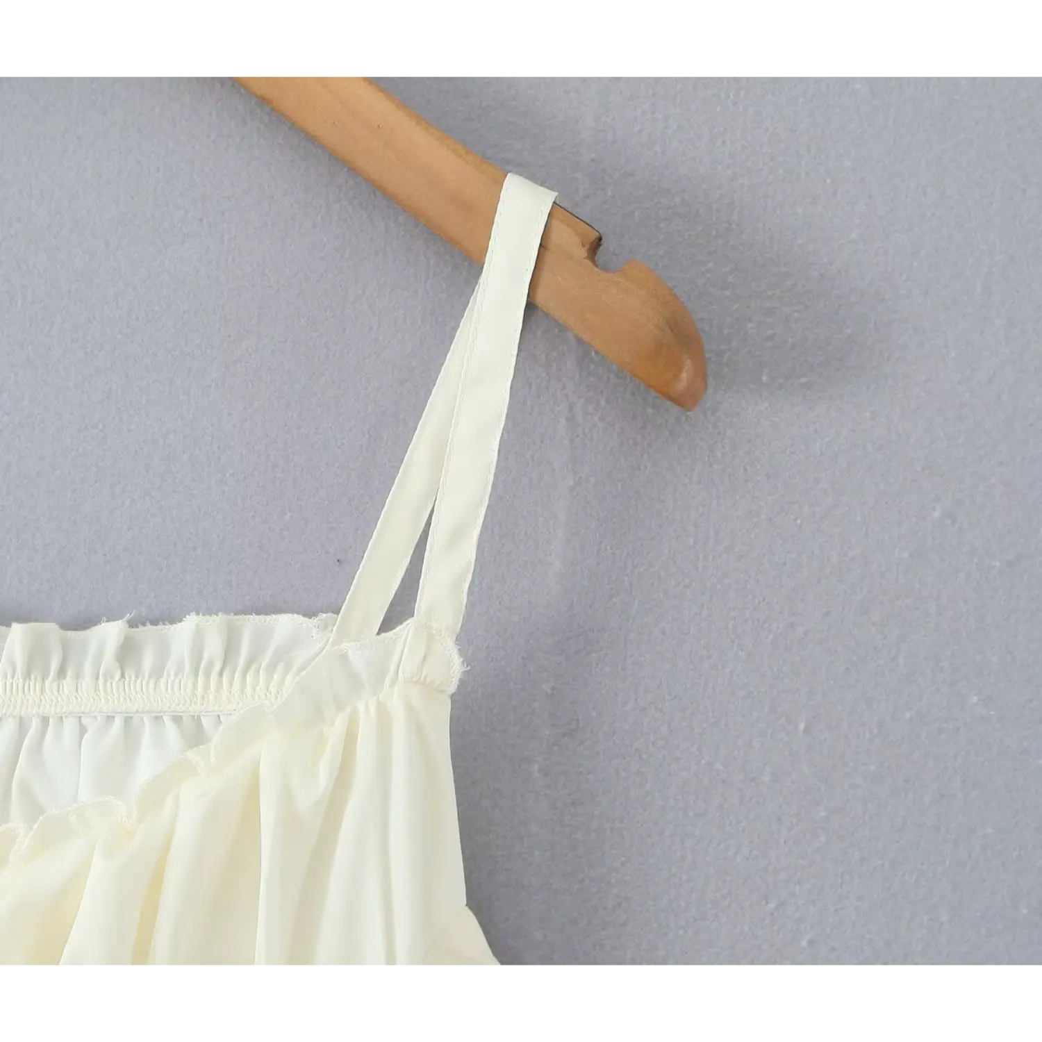 Close‑up double cami strap shoulder seam detail cream mini dress on wooden hanger