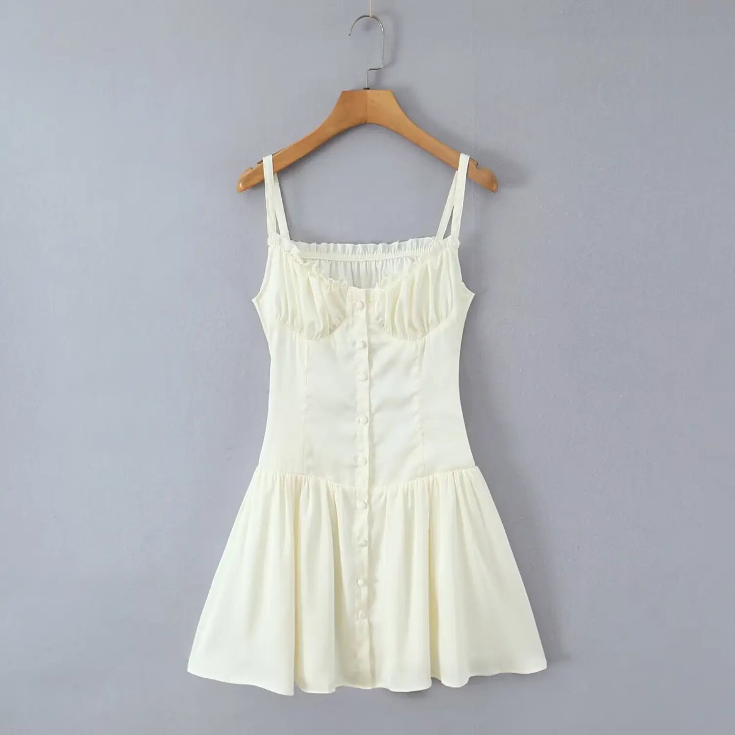 Hanging shot cream cami mini dress wooden hanger grey wall front full view button front design
