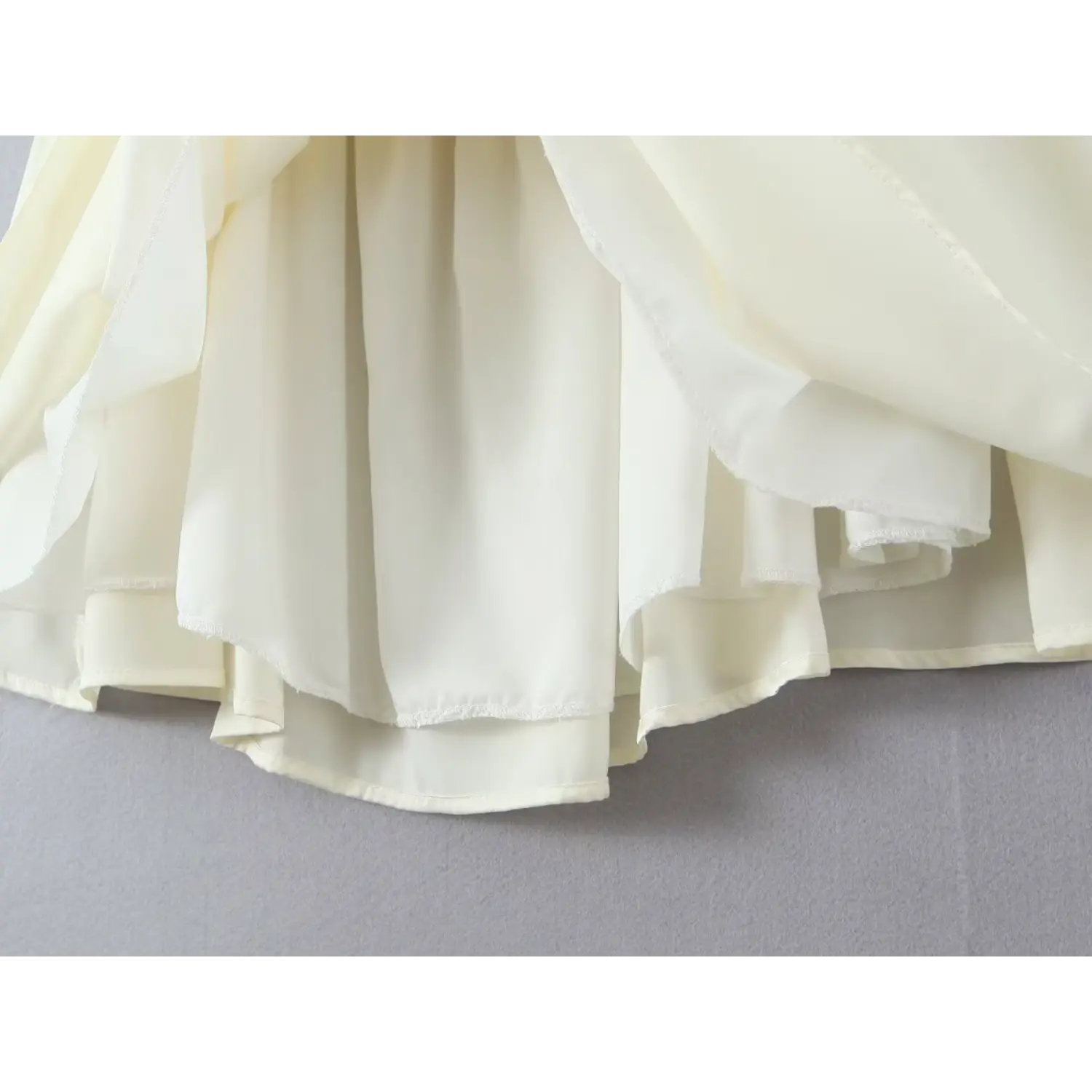Close‑up flared skirt hem and inner lining construction cream cami mini dress