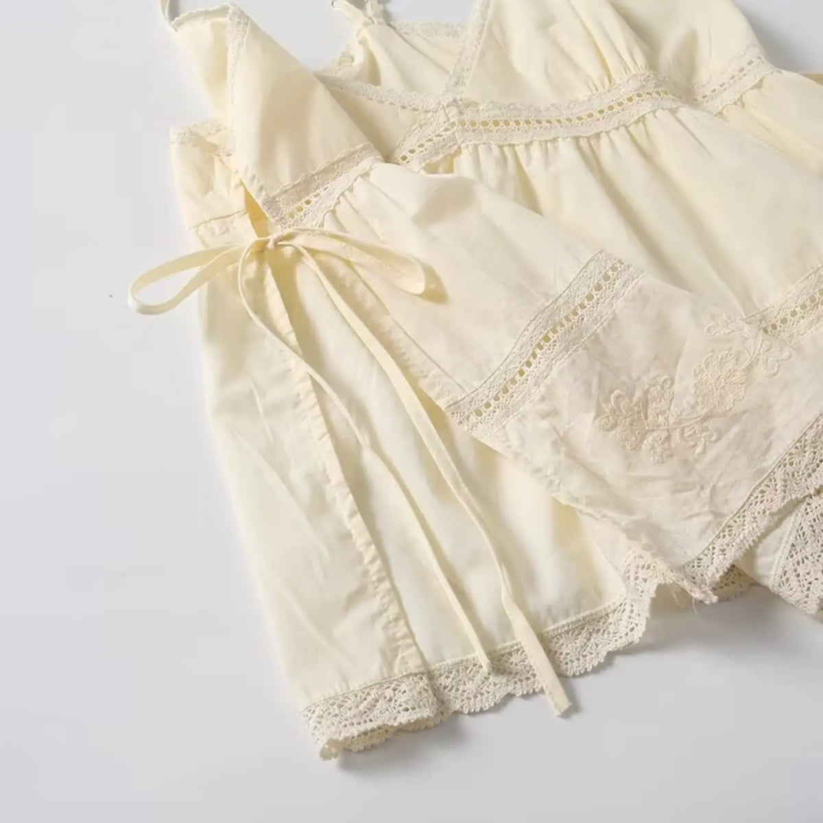 Side view of cream lace cami, display side drawstring tie and lace hem embroidery detail
