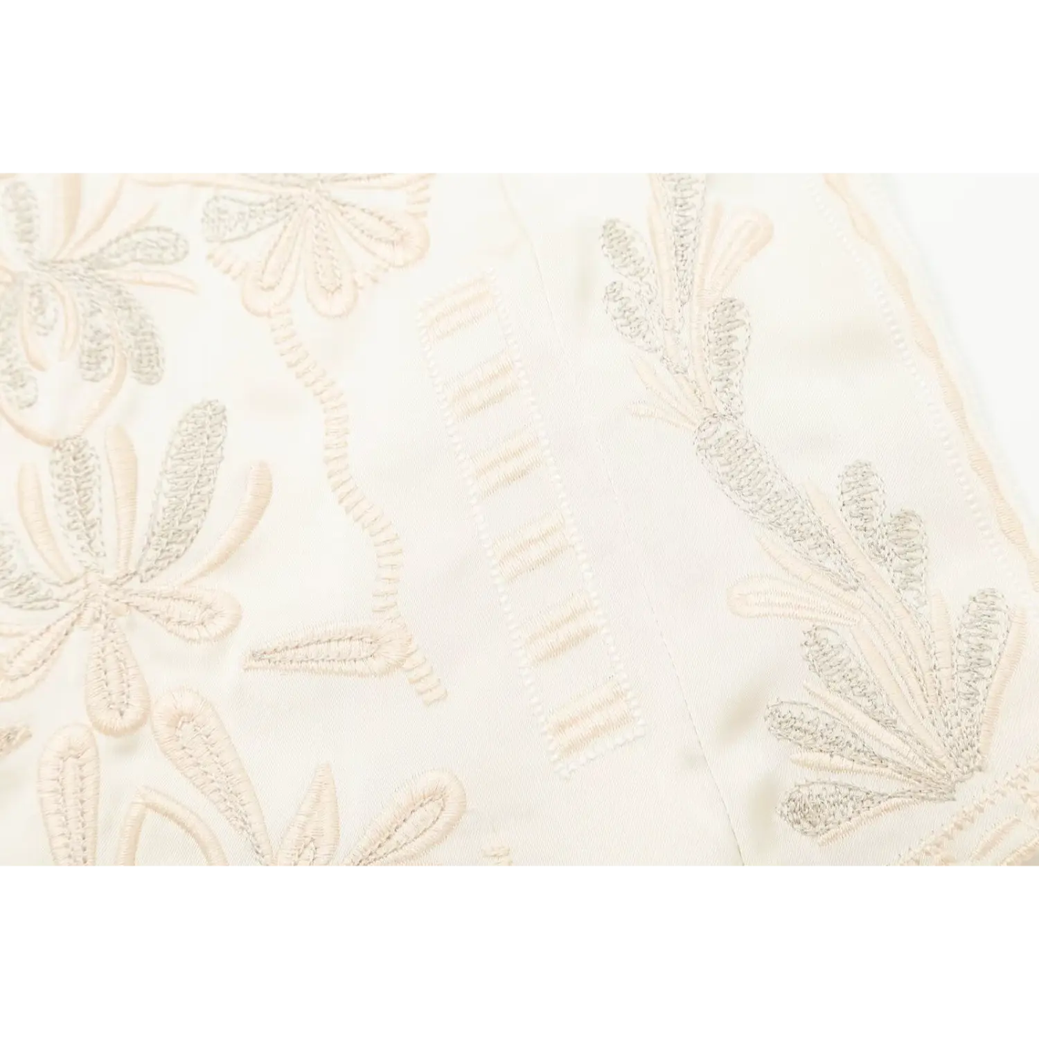 Close‑up of decorative vertical embroidered seam details on cream camisole top