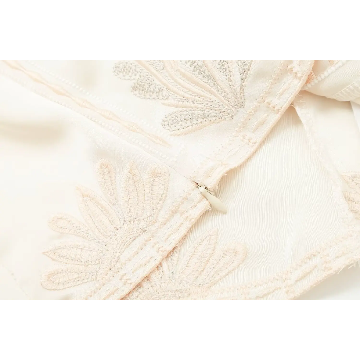 Close‑up of hidden side zipper on cream floral embroidered satin camisole top
