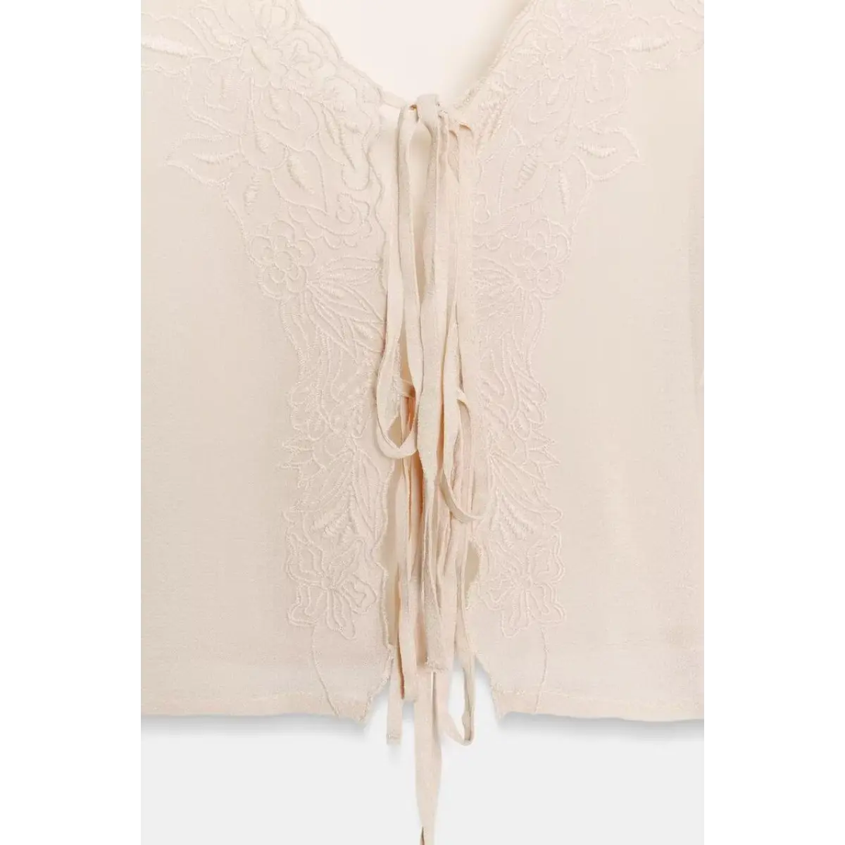 Close-up of the tie-front closure on a cream chiffon blouse, featuring delicate lace embroidery and fabric ties.