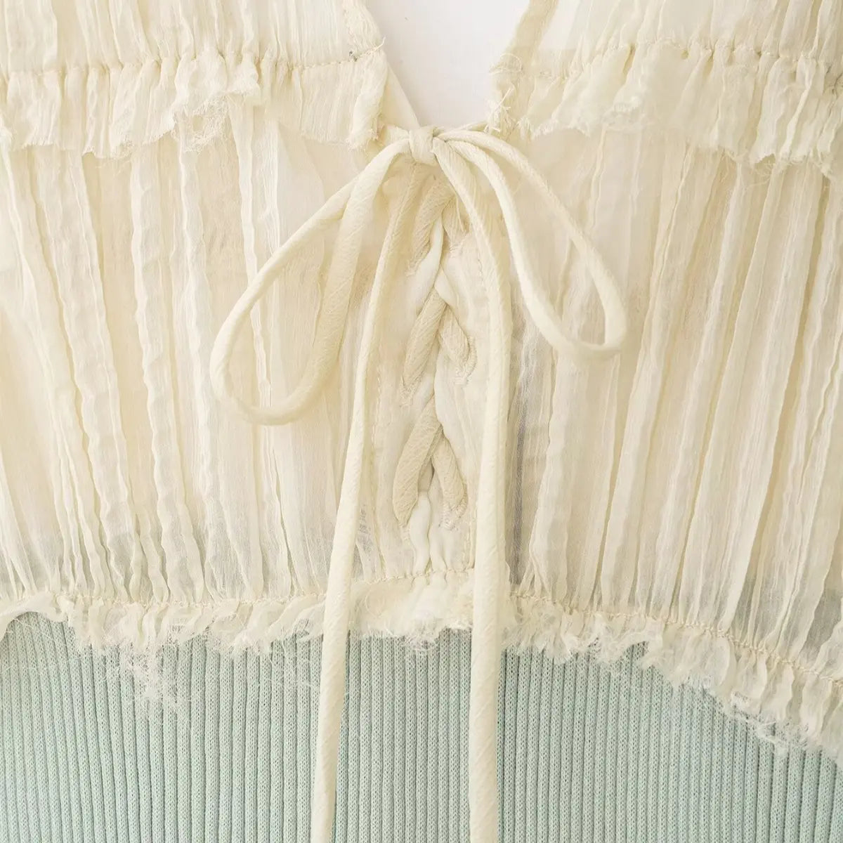 Close-up of the lace-up drawstring on the cream chiffon cami top, showing the tied bow and ruffled chiffon trim
