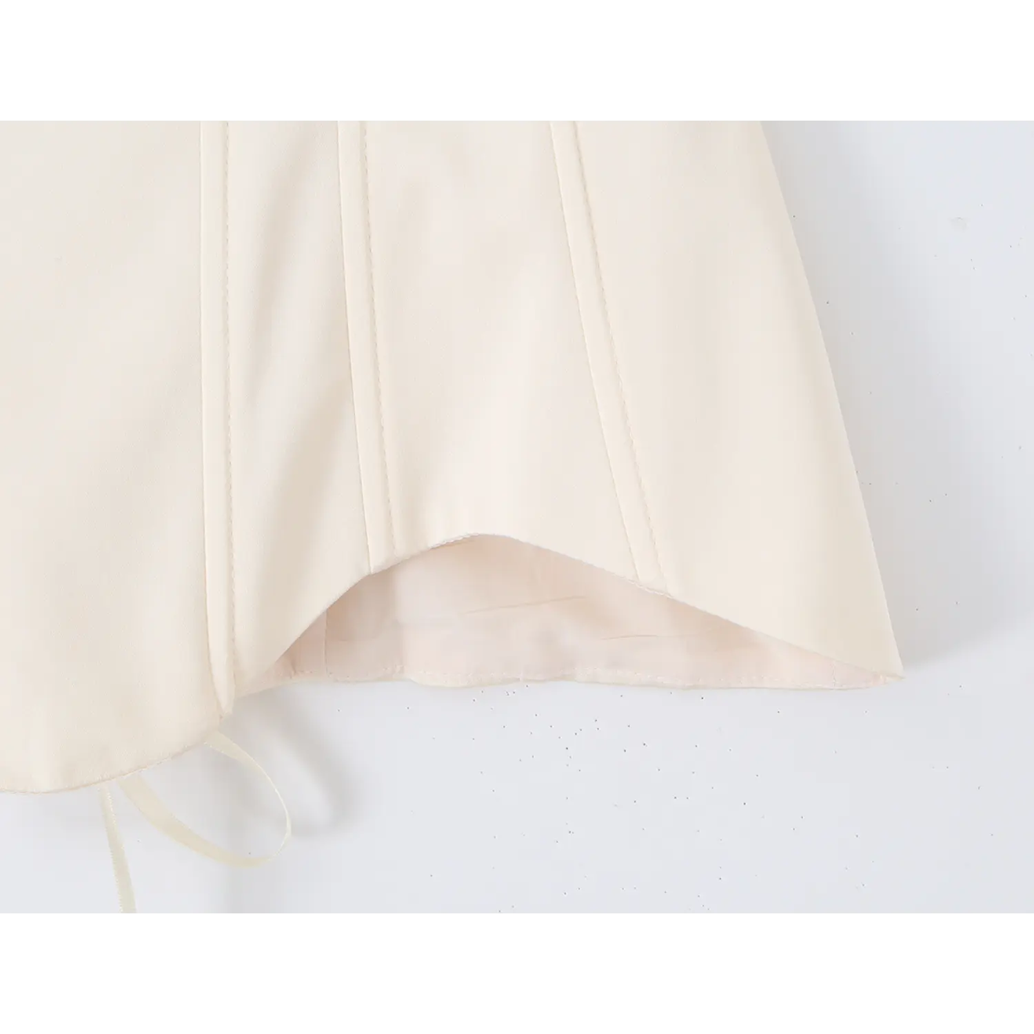 Close‑up of curved scalloped hem and inner lining fabric of cream boned corset top