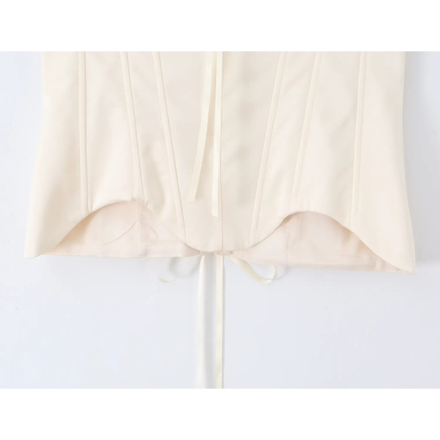 Bottom view of cream strapless corset top, scalloped hem with lace‑up ribbon tie closure