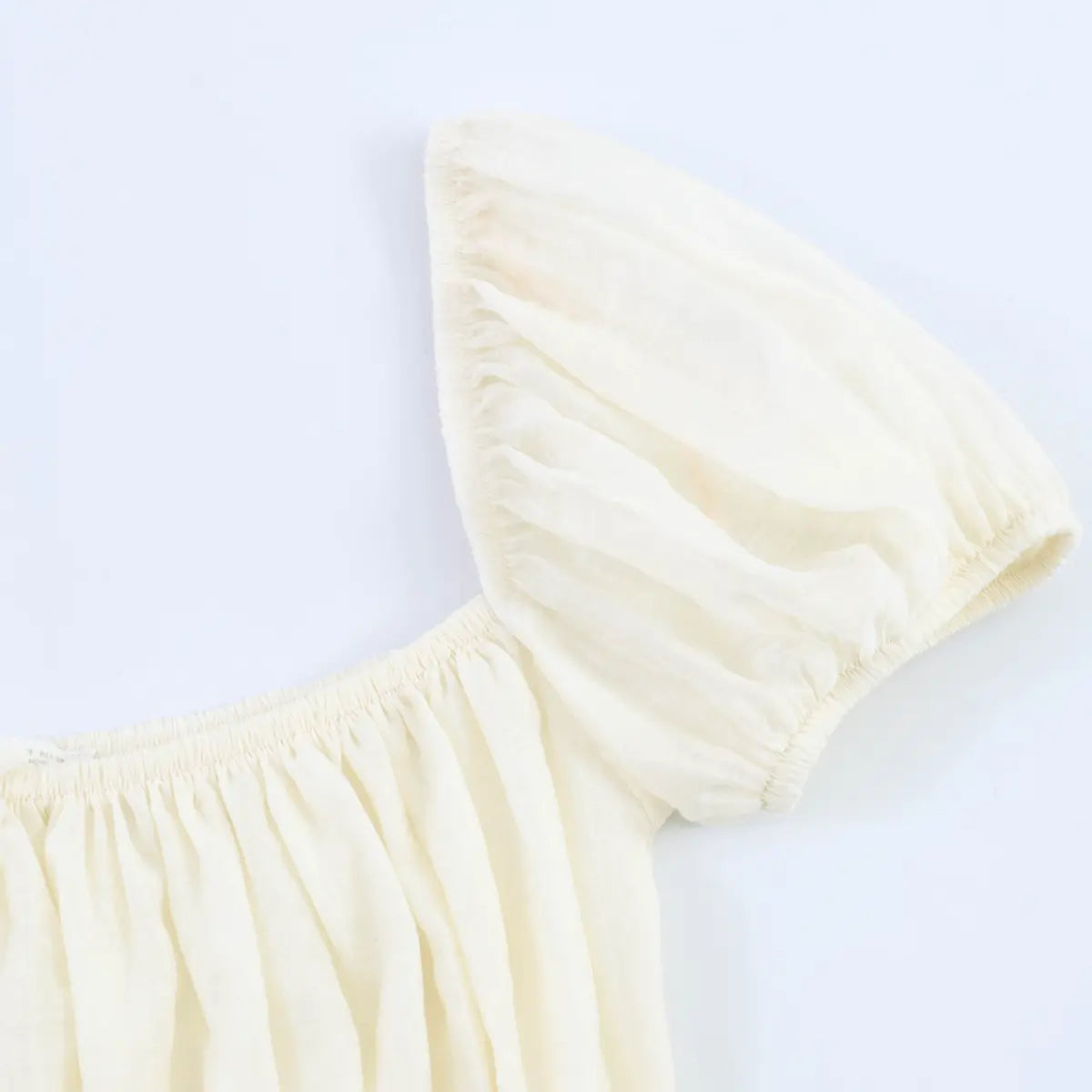 Close-up of the gathered puff sleeve and elasticated cuff on the cream corset-style top.