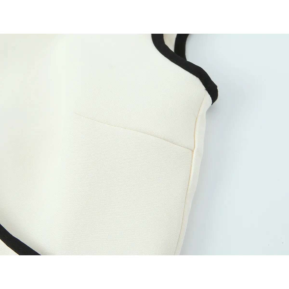 Close-up of the bodice side seam on the cream qipao dress, showing the black contrast trim and structured princess seam
