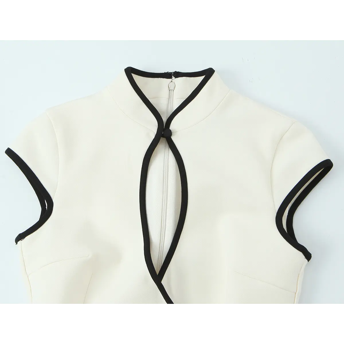 Front view of the cream crepe qipao dress, showing the mandarin collar, black piping trim, keyhole cutout, and cap sleeves