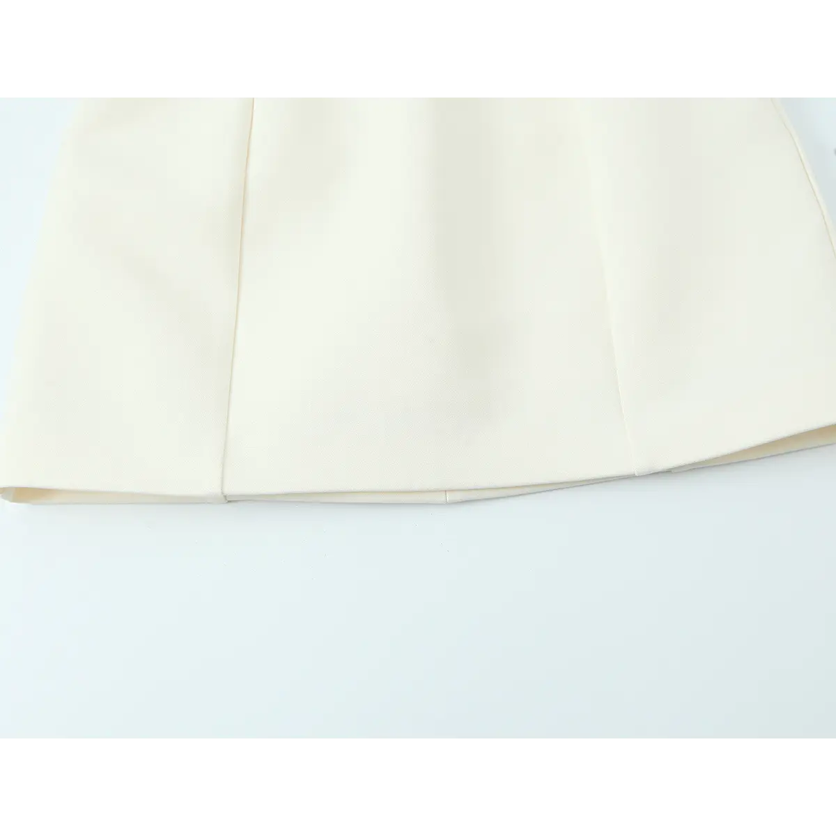 Hem view of the cream crepe qipao dress, showing the smooth A-line skirt and clean pressed seams