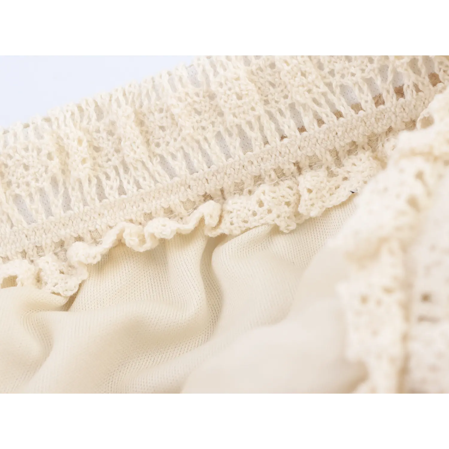 Close-up of crocheted lace frill edge and soft inner lining of cream midi skirt