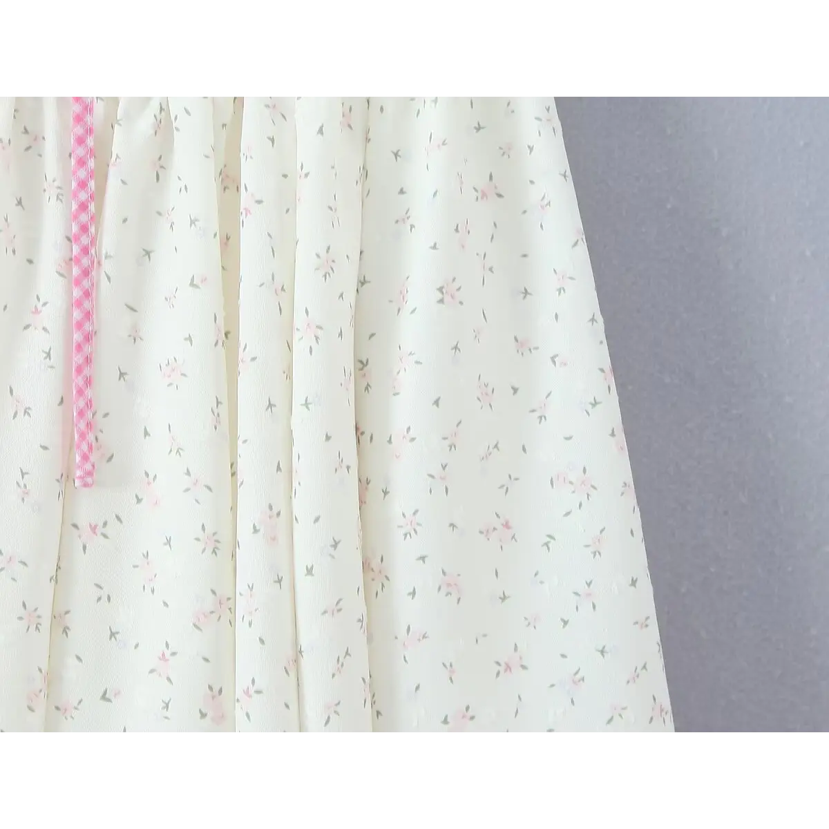 Close-up of the ditsy floral print fabric on the skirt, showing the small pink flowers and green leaves.