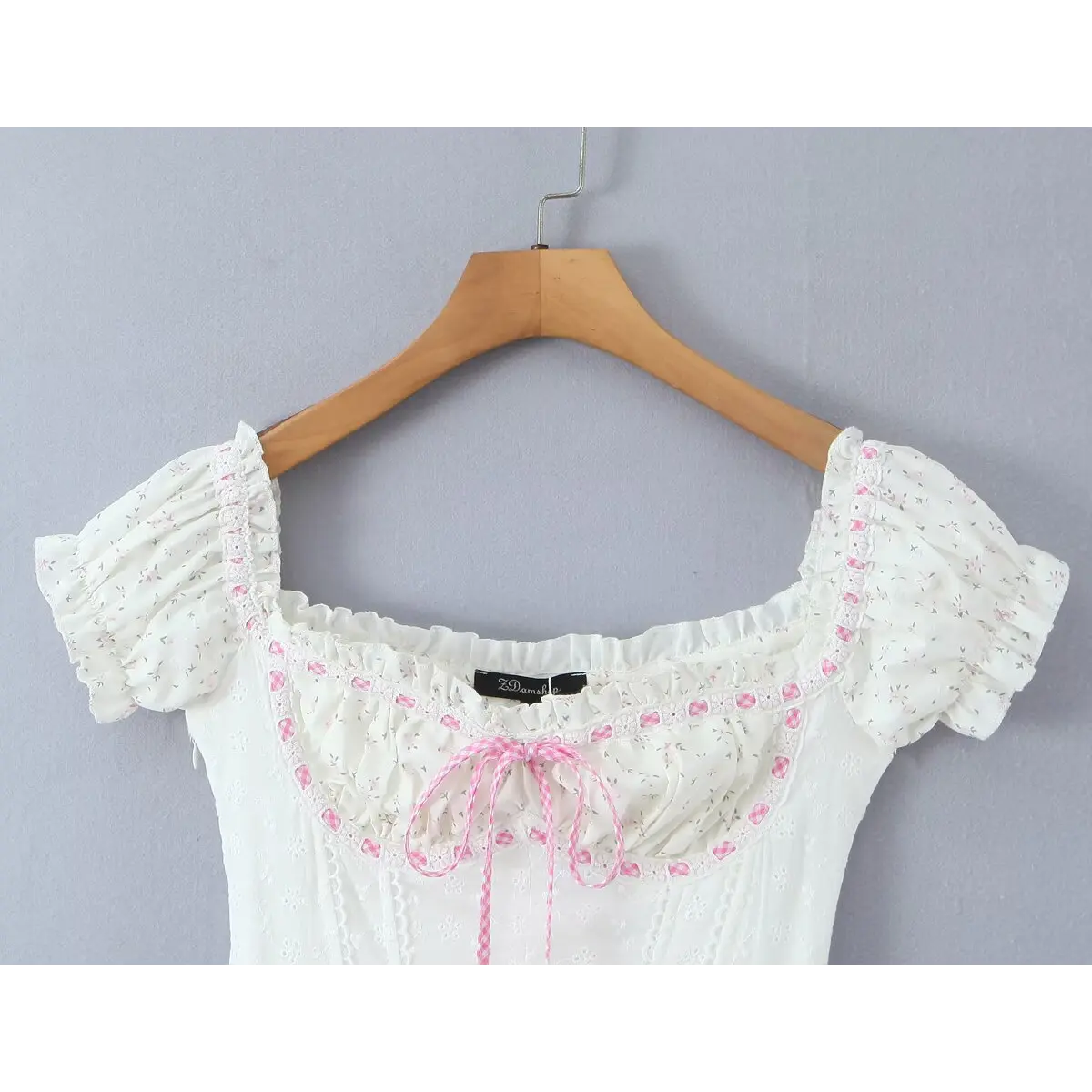 Close-up of the square neckline, ruffled trim, and front pink gingham ribbon tie.