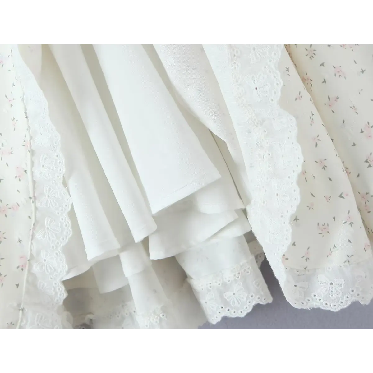 Close-up of the layered skirt construction, showing the smooth inner lining, outer floral print fabric, and delicate butterfly lace trim at the hem.