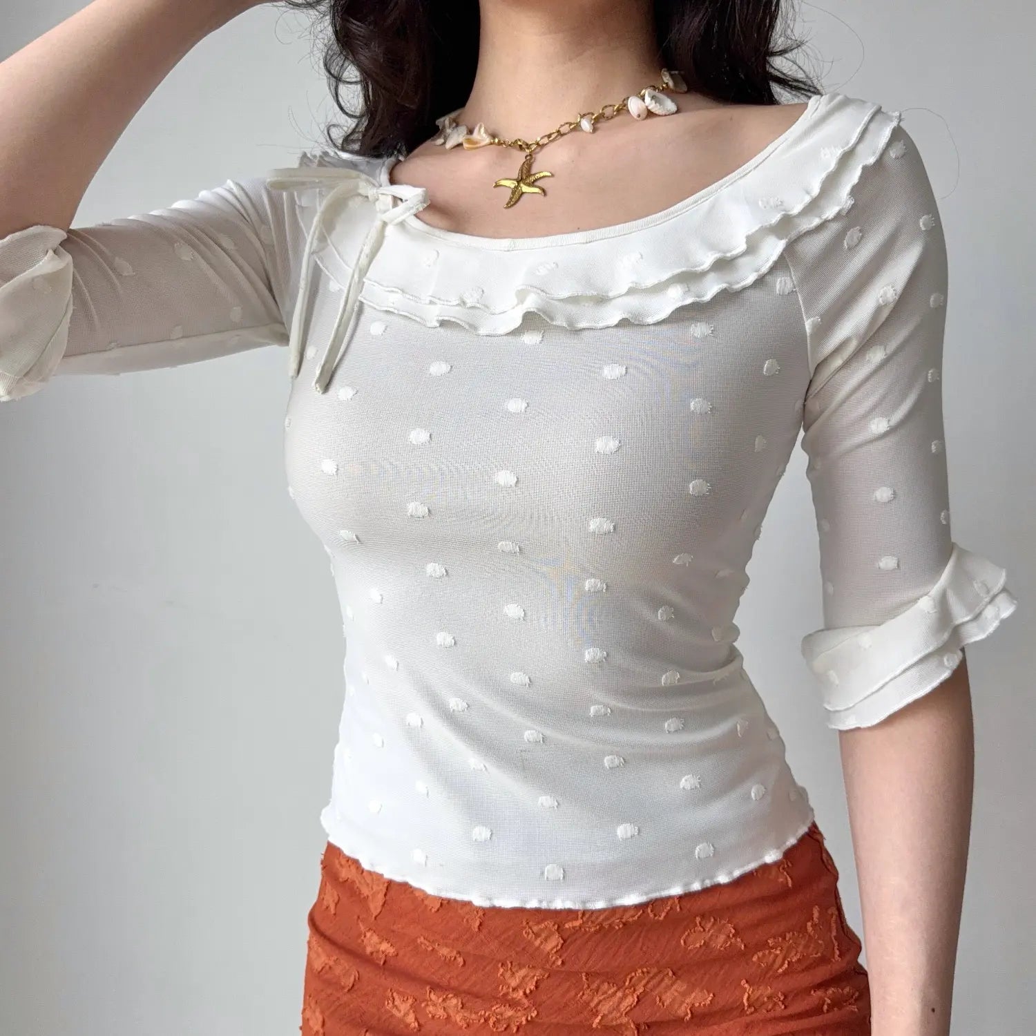 Front lifestyle shot on model of white textured dot mesh top, wide boat neck, frill trim neckline, slim casual mid sleeve blouse