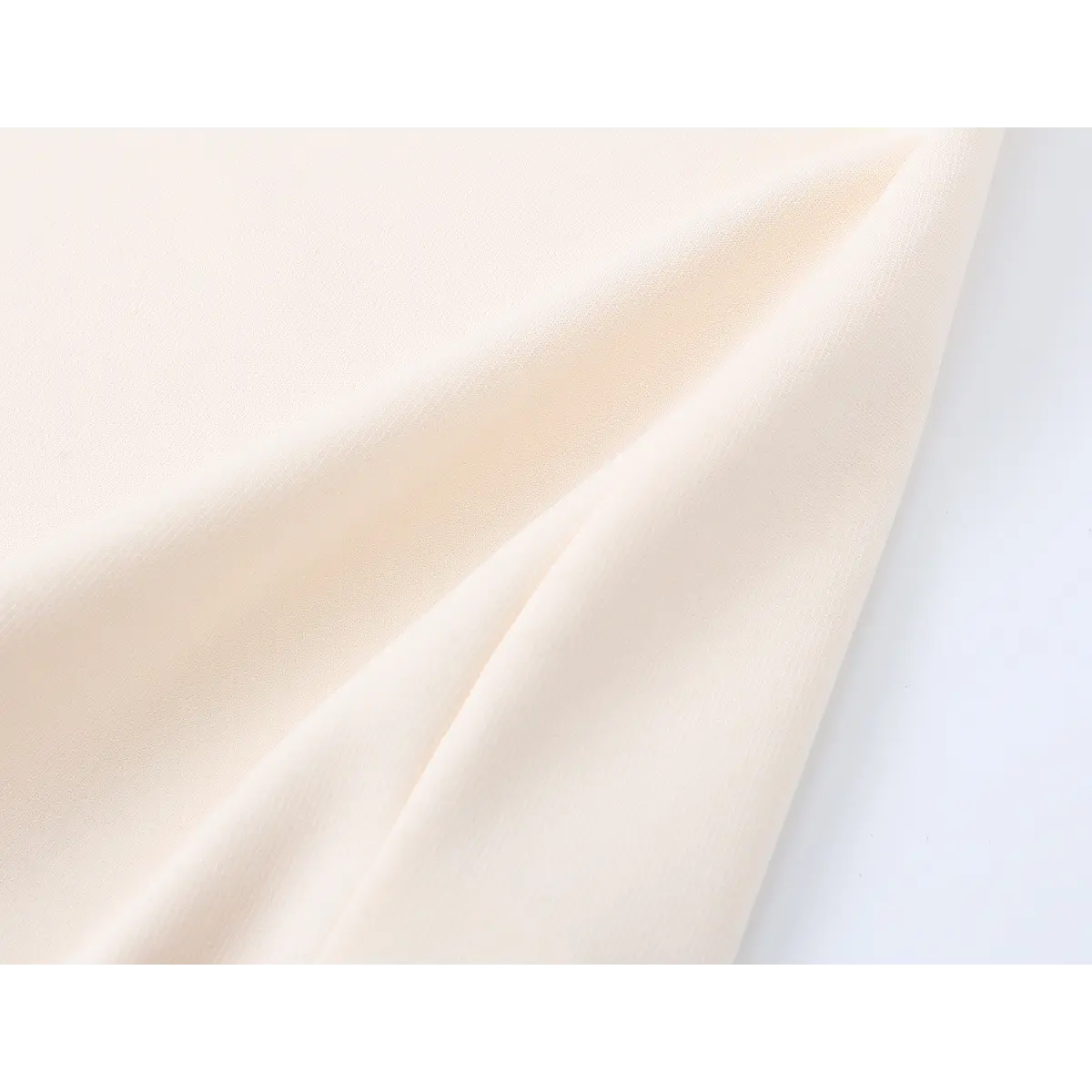 Close-up view of the dress's creamy fabric, highlighting its smooth texture and soft drape.